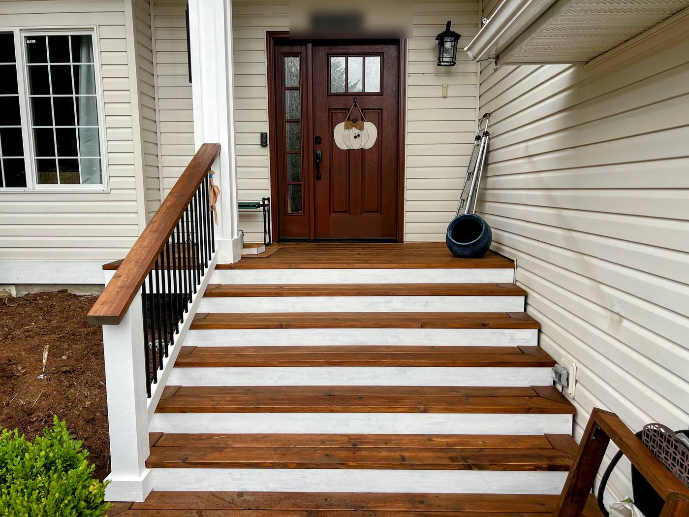 Cedar deck stairs with stained treads, white risers and black metal balusters leading to a front entry, built by Premier Construction Services in Whatcom County