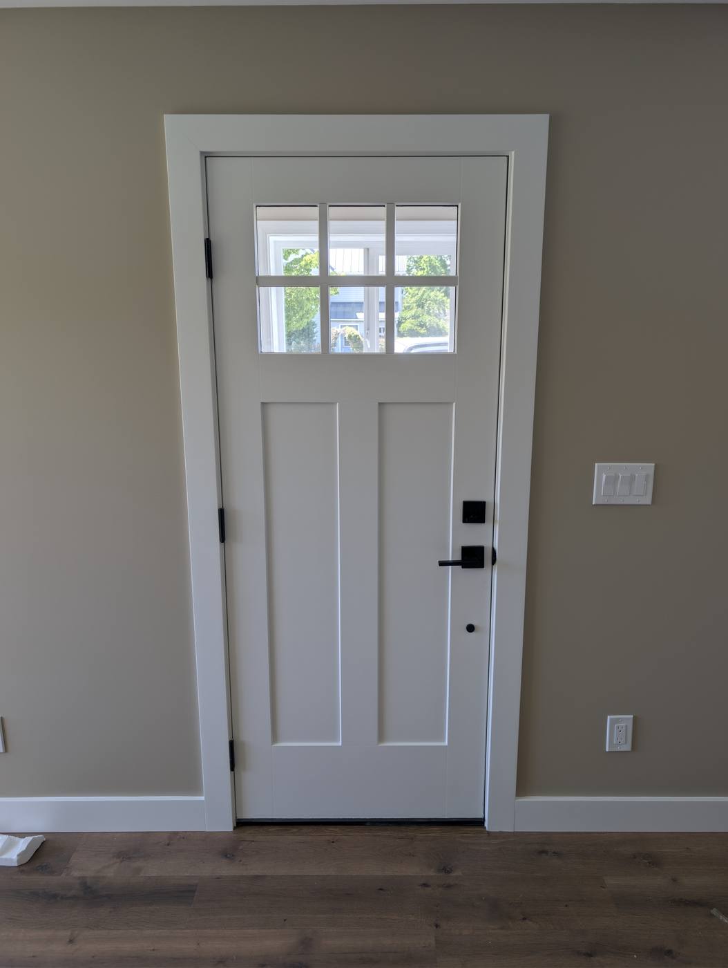 New white Craftsman-style entry door with divided light glass and trim installed in a Ferndale, Washington home by Premier Construction Services