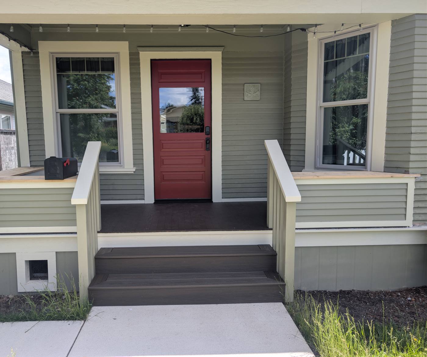 Rebuilt Craftsman front porch in Bellingham, Washington with new composite decking, steps, railings and a red entry door by Premier Construction Services
